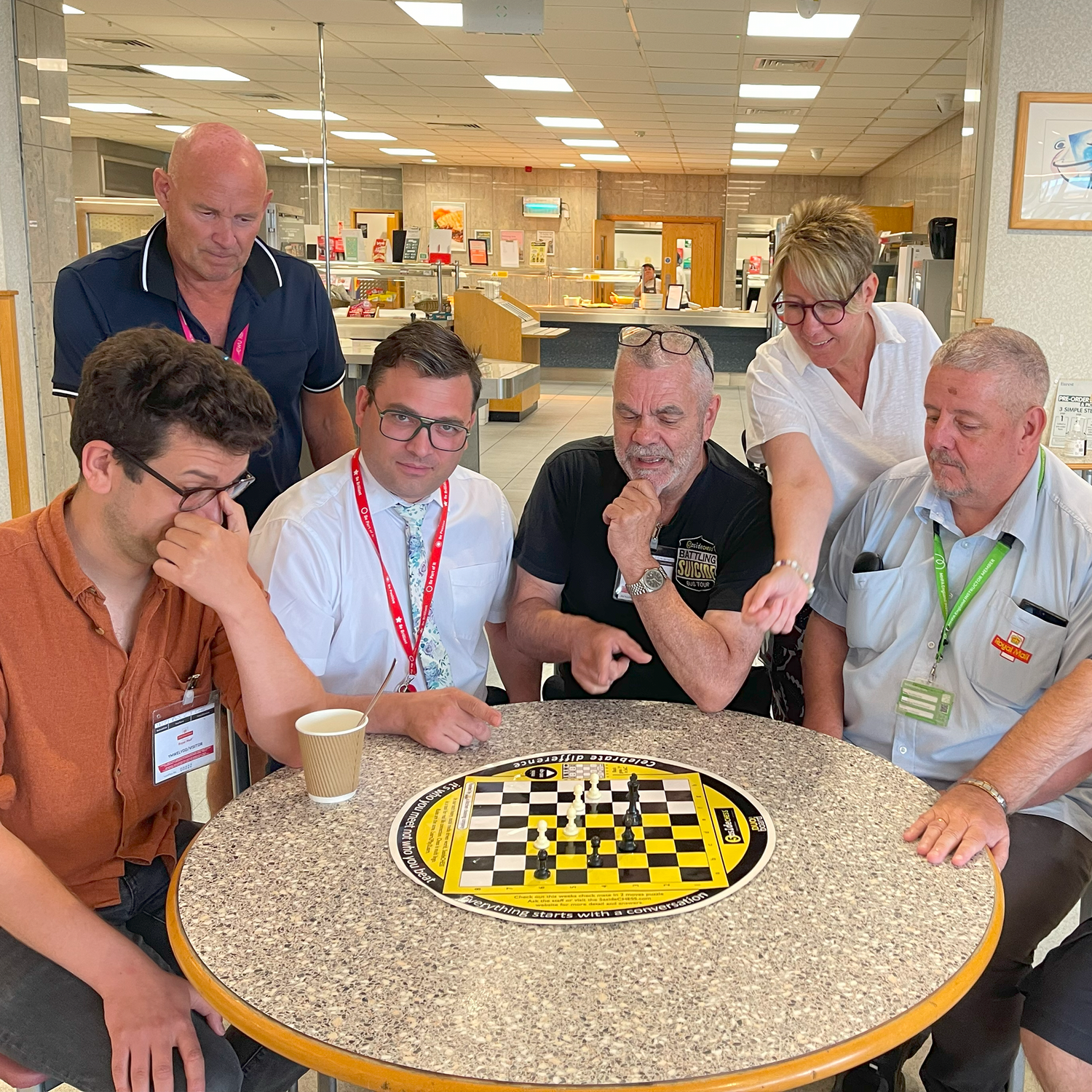 people discussing and playing 5asideCHESS in a cafeteria setting